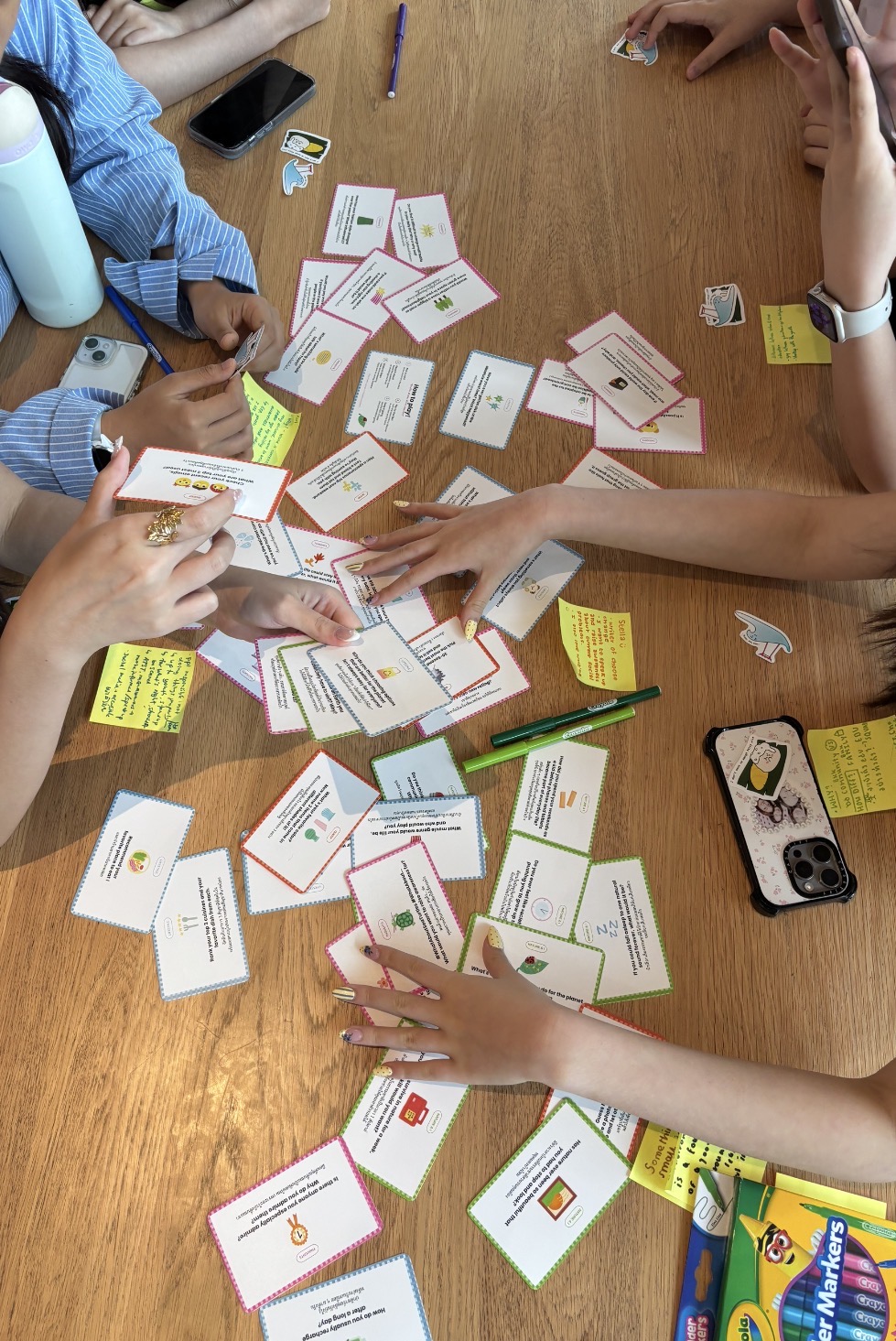Hands reaching over the Earth&Us Cards spread across the table